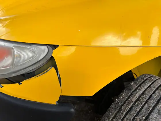 Close view of a damaged vehicle front bumper and headlamp