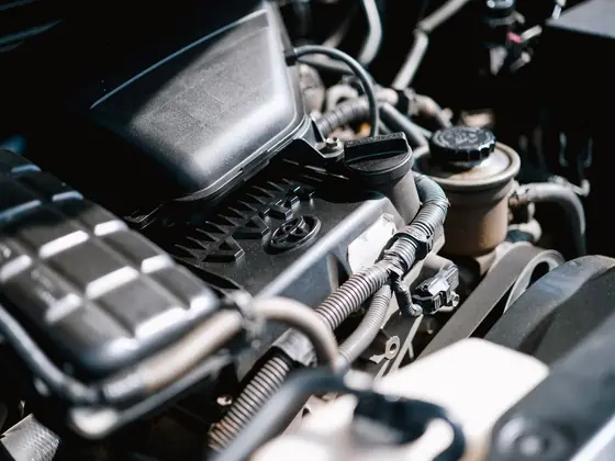 Close view of an engine bay showing cabling, hoses and cast components