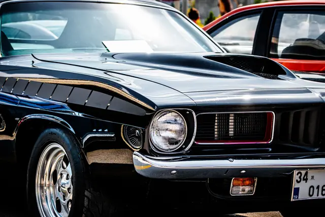 Front three-quarter view of a black 1970s American muscle coupe with chrome bumper and quad headlamps