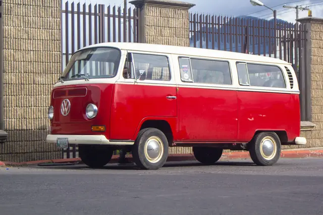 A red and white classic Volkswagen Type 2 van parked on a street