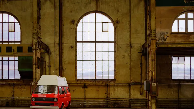 A classic van parked inside a large industrial warehouse space